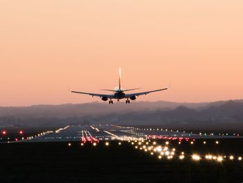 Airplane flying in sky at sunset