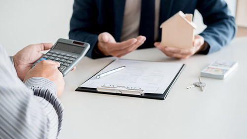 Midsection of man holding mobile phone on table