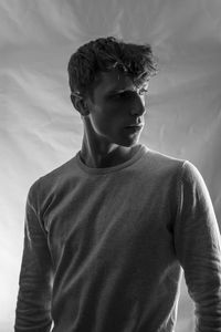 Young man looking away against white background