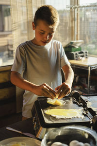 Boy preparing fried egg in kitchen at home