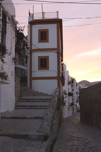 Footpath leading towards houses in town against sky