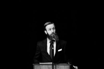 Mid adult man standing against black background