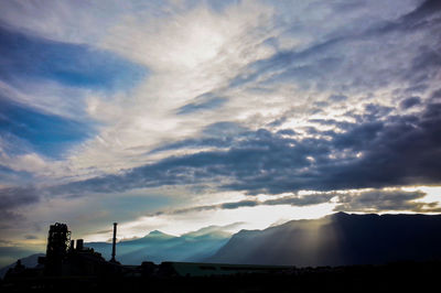 Silhouette of factory against sky during sunset