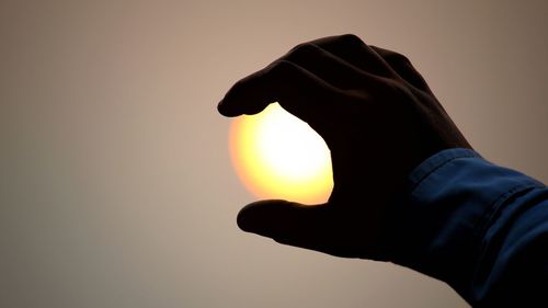 Close-up of silhouette hand against sky during sunset