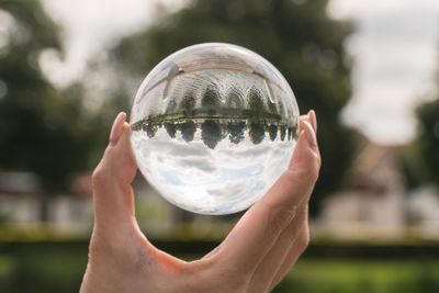 Cropped hand of woman holding crystal ball in park