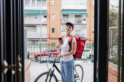 Smiling delivery person with backpack looking away