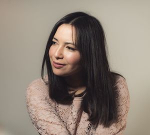 Smiling woman looking away against gray background