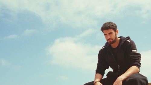 Low angle view of man sitting against sky