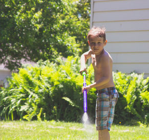 Full length of shirtless boy standing in yard