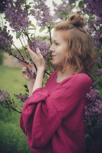 Woman standing by pink flowering plants