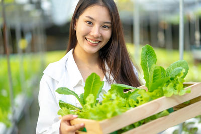 Portrait of young woman standing by plants