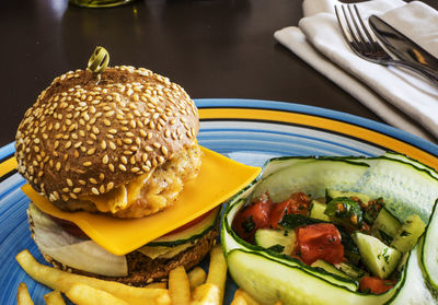 Close-up of hamburger with french fries and salad served in plate on table