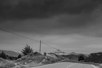 Road leading towards mountain against sky