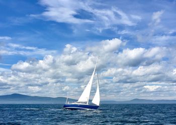 Sailboat in sea against blue sky