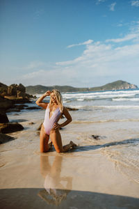 Full length of woman standing at beach against sky