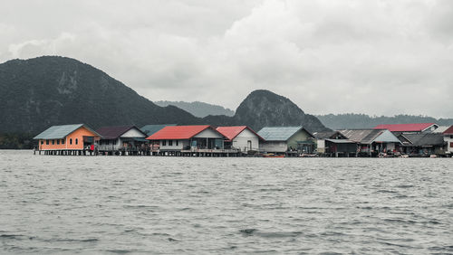 Houses by sea and mountains against sky