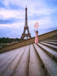 Woman with tower against cloudy sky