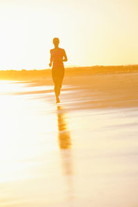 Woman running on beach at sunset