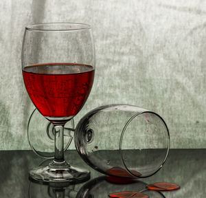 Glass of wine on a high-gloss areas and a backdrop fabric.