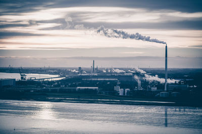 Smoke emitting from factory against sky during sunset