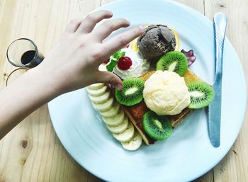 Cropped hand by dessert on table