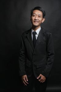 Portrait of businessman standing against black background