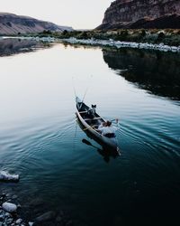 Man sailing on boat in lake against sky