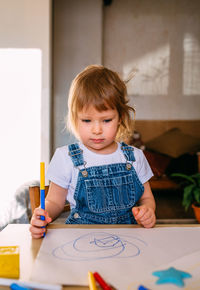 Small child at home at the children's table draws with felt-tip pens.