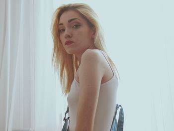 Portrait of beautiful young woman standing against white wall