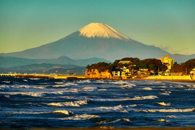 Scenic view of ocean against snowcapped mountain in the morning