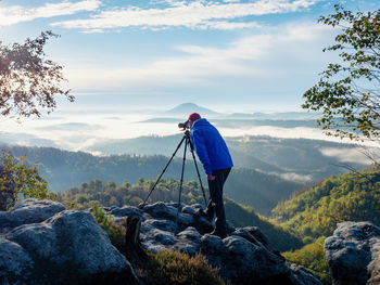 Photographer framing scene in viewfinder. camera on tripod for taking pictures of misty scenery