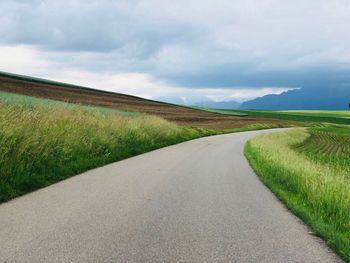 Road amidst field against sky