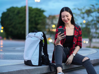 Full length of woman using phone while sitting in bus