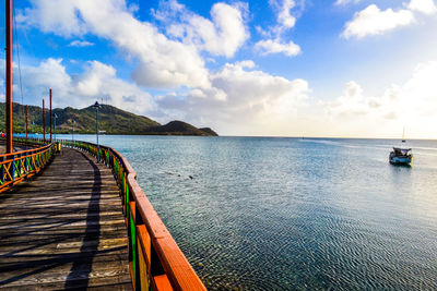 Pier on sea against cloudy sky