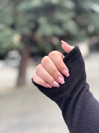 Cropped hand of woman with painted fingernails against trees