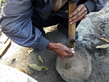 Low section of man holding wooden stick on road