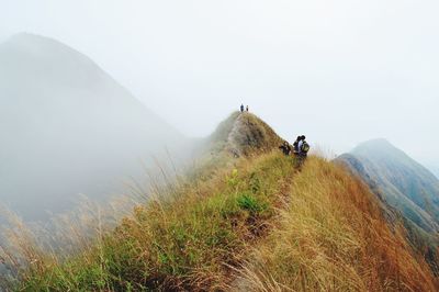 People on top of mountain against sky