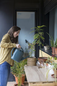 Woman standing by potted plant on table