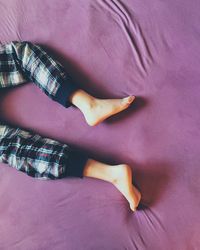 Low section of boy lying on bed at home