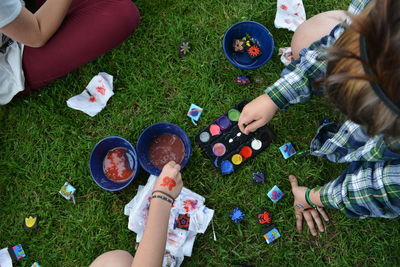 Cropped image of children with water colors on field