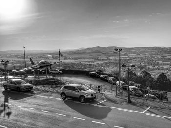 Cars on road against cloudy sky