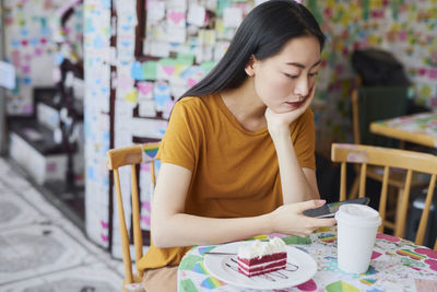 Young woman looking away while sitting on table