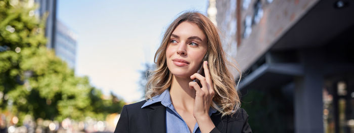 Portrait of young woman standing in city