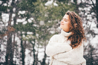 Young woman standing against trees during winter