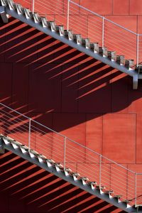 Low angle view of steps and staircases on red wall during sunny day