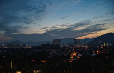 Illuminated cityscape against sky during sunset