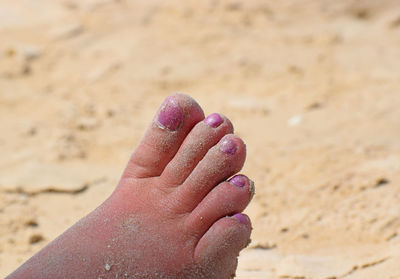 Cropped leg of woman covered in sand