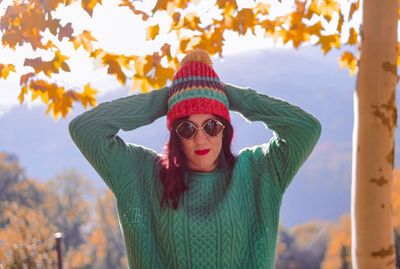 Young woman wearing knit hat and sunglasses at public park during autumn