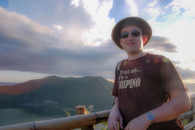 Young woman wearing sunglasses standing on mountain against sky