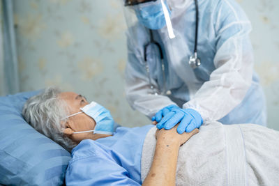 Doctor wearing flu mask examining senior woman at hospital